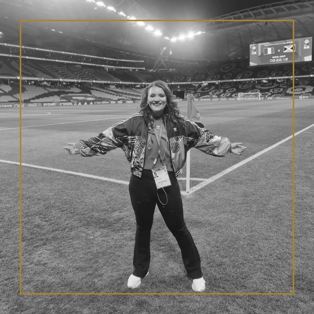 Woman smiling with arms outstretched on the field at the FIFA Women’s World Cup.