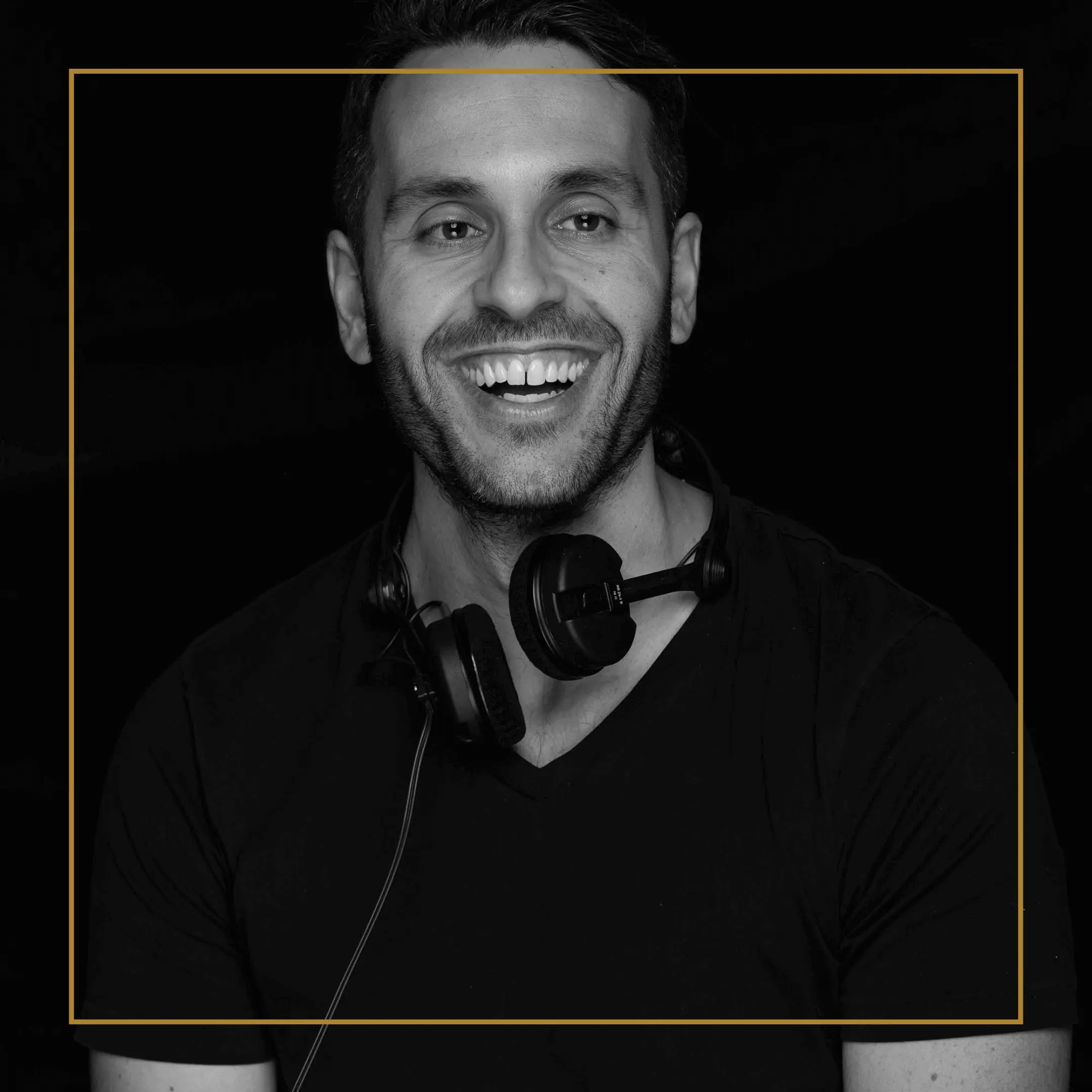 DJ Michael smiling, wearing headphones around his neck against a dark background