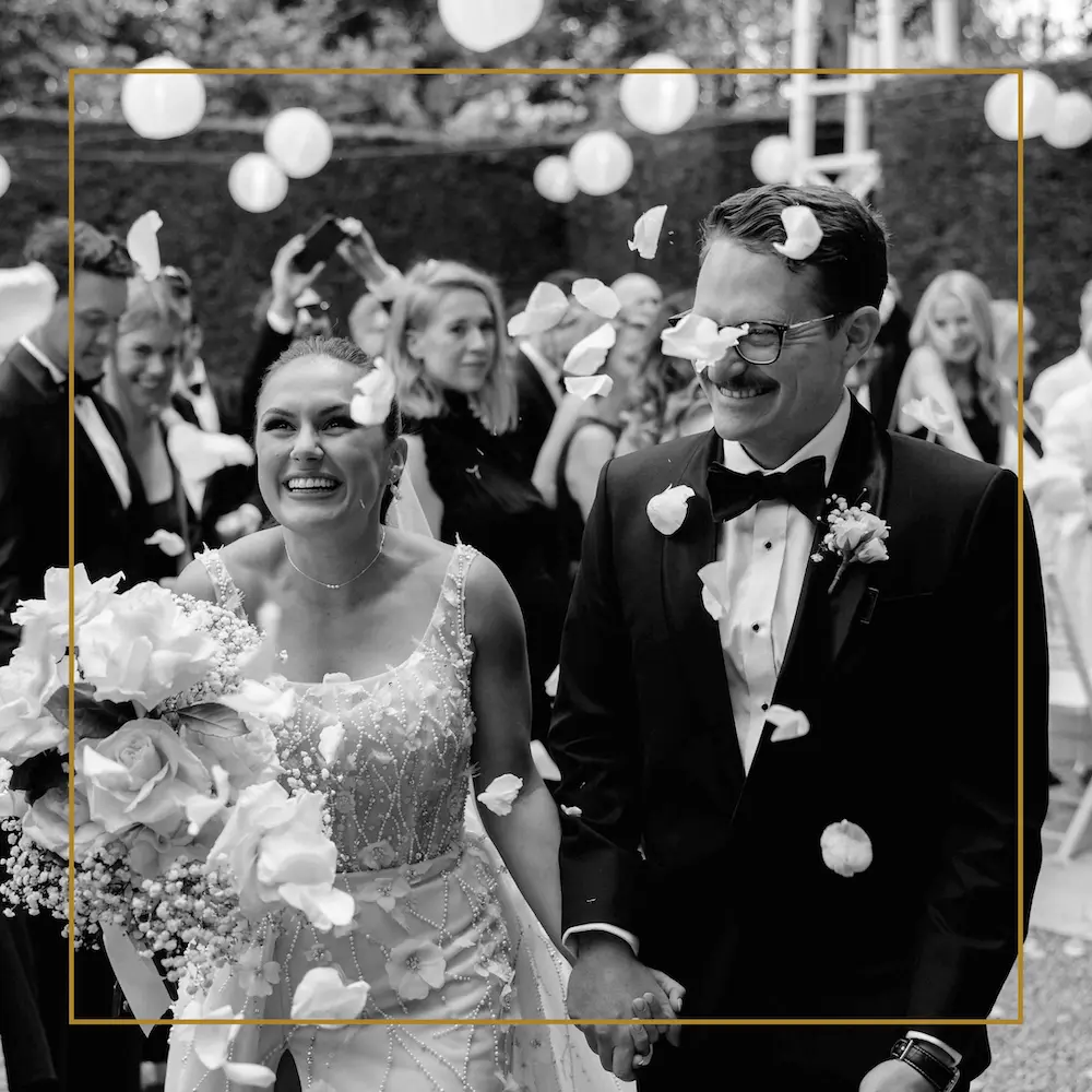 Bride and groom smiling as guests throw flower petals during their Perth wedding celebration complete with DJ.